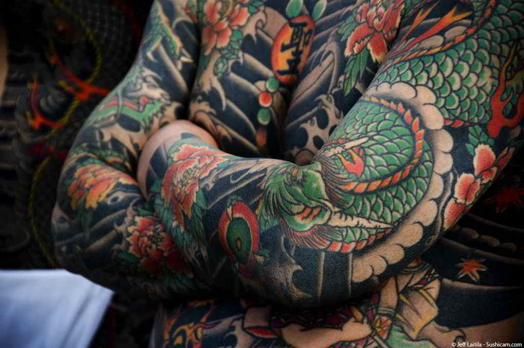 Un hombre cruzado  de brazos con tatuajes japonenes