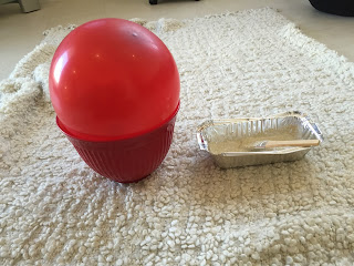 a red balloon blown up, sitting in a red bowl, with a tray of gold glitter and mod podge mixed, sitting next to it