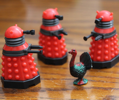 doctor who dalek toys have guns pointed at a turkey figure