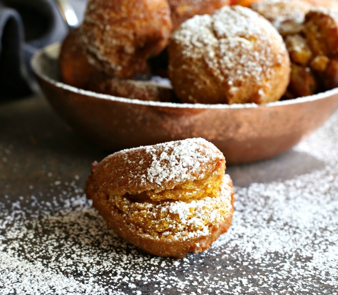 Recipe for sweet fried pumpkin doughnut fritters, flavored with cinnamon and ginger and dusted with powdered sugar.