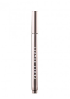 A thin gold cylindrical eyeliner with a black bottom and black tip inside a gold cylindrical lid on a bright bavkground.