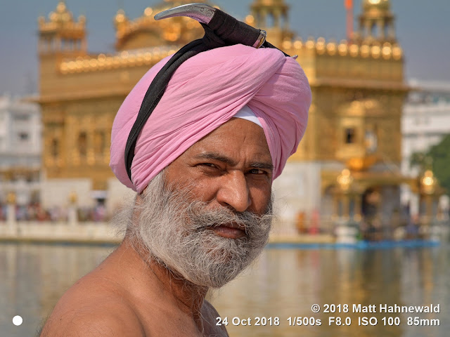 matt hahnewald photography; facing the world; people; character; head; face; eyes; expression; looking camera; full beard; barechested; pink; dastar; turban; dagger; kirpan; consent; respect; living; culture; tradition; lifestyle; religion; religious; sikh; sikhism; follower; faith; khalsa; temple; holy pond; pond of nectar; sarovar; golden temple; sri harmandar sahib; tourist attraction; devotee; worshiper; amritsar; punjab; india; asia; asian; indian; punjabi; individual; one person; male; elderly; man; photo; detail; background; physiognomy; nikon D610; nikkor afs 85mm f1.8g; 85mm; 4 x 3 ratio; resized; 1200 x 900 pixels; horizontal; street; portrait; closeup; headshot; two third view; sideways glance; outdoor; sunlight; color; posing; iconic; manly
