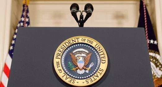 Close-up photo of Presidential speaking podium with two microphones and the seal of the President