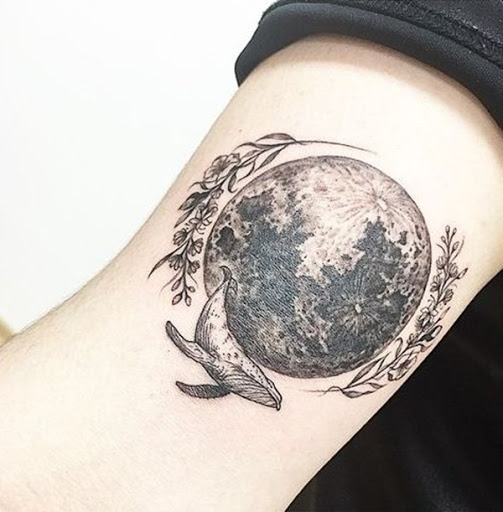 A lua funciona como a peça central deste tatuagem que casais aparentemente não-relacionadas de imagens, incluindo flores e uma baleia azul.