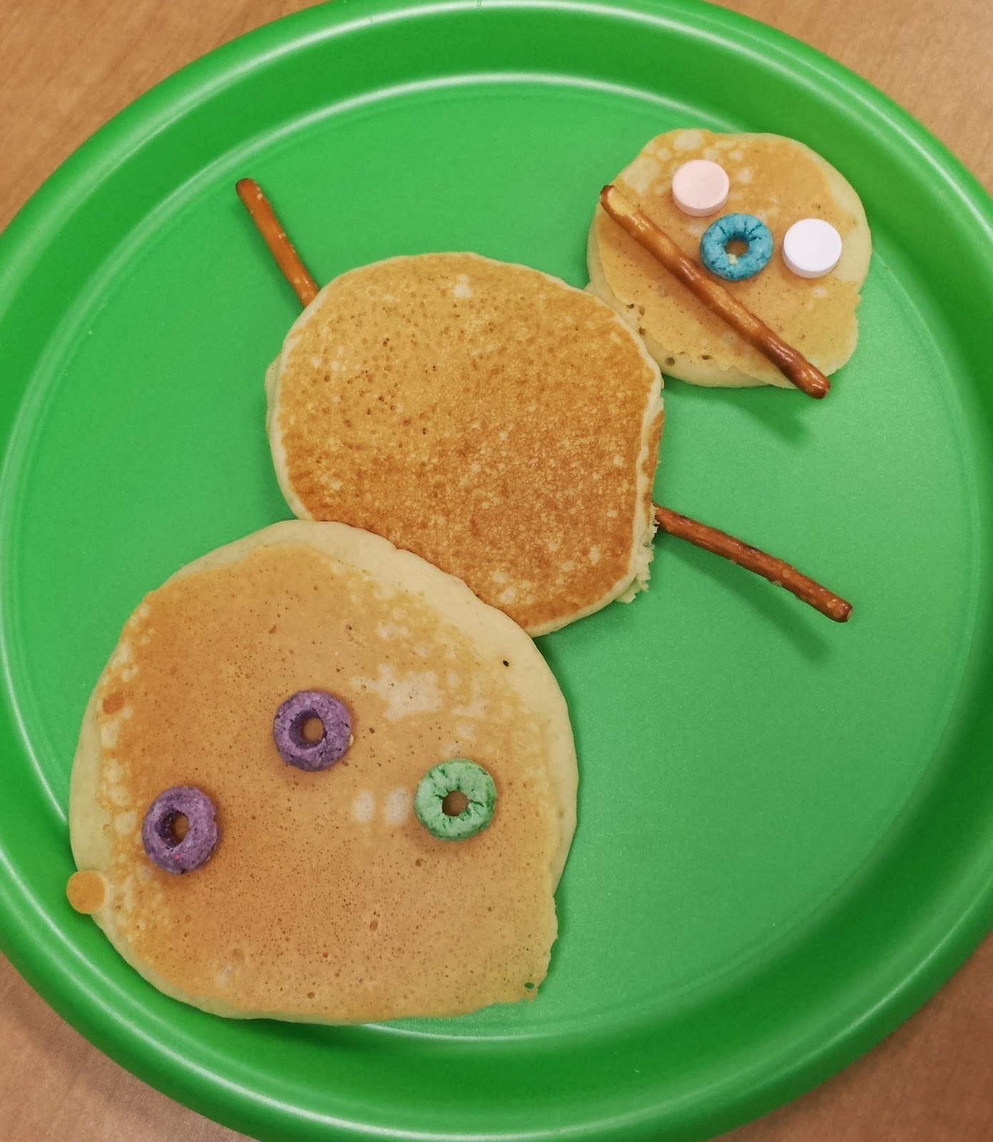 photo of snowman made out of pancakes on a green plate