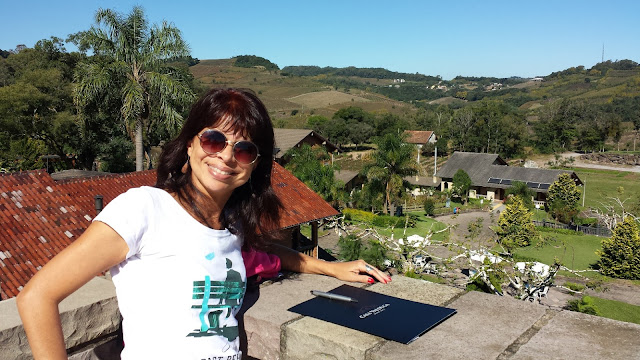 A vista da Villa Valduga, em Bento Gonçalves moça sorri com cenário de montanhas verdes