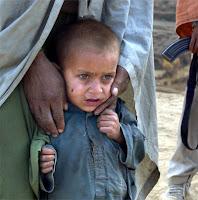 A child is held by an anti-Taliban solider December 14, 2001 on the road to front lines near the Tora Bora area of Afghanistan. Clouds of smoke from U.S.-led bombing billow over Al-Qaeda positions as American and anti-Taliban forces continue to try to dislodge troops loyal to Osama bin Laden from the mountainside.