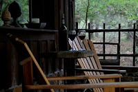 outdoor chairs on porch with wine glasses on table