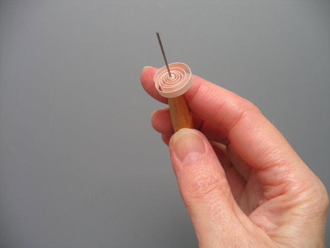 hand holding a quilled loose coil on a needle tool