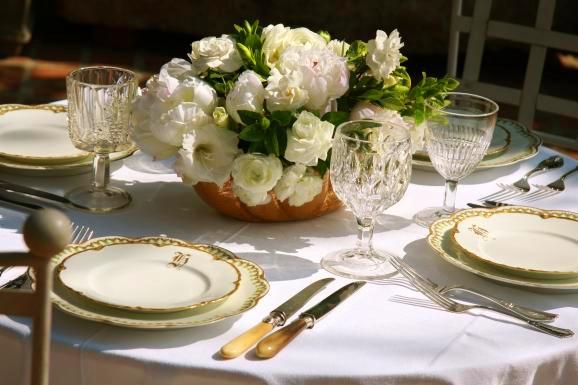 White peonies and gardenias in a gold bowl compliment the gold rimmed white 