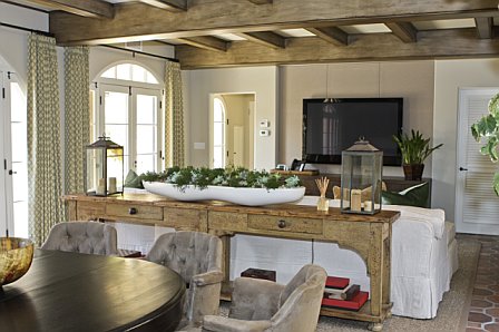 Garage was turned into a media room after remodeling with natural wood beamed ceiling, spanish tile floor, white sofa and a flat screen TV