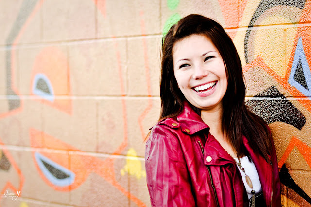 Happy girl at engagement shoot at the arts district in las vegas smiling and leaning up against a wall with graffiti.