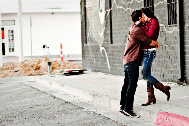 An engaged couple on a photo shoot downtown las vegas with their arms around each other kissing 