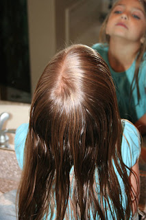 Back view of a young girl having her hair styled into “Double-twist" ponytail
