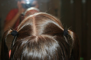 Back view of young girl's hair being styled into "4 Messy-Pigtail Twists" hairstyle