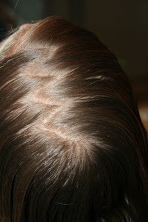 Close up view of young girl's hair being styled into "Y" braid hairstyle