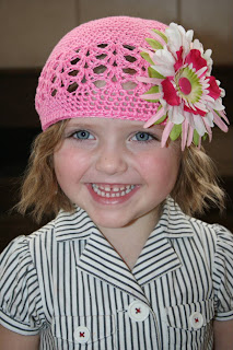 Young girl modeling a pink hat with a multi-color flower on it