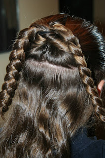Back view of young girl's hair being styled into "Flip Braided Heart" hairstyle
