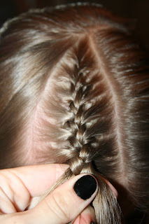 Close up view of a young girl's hair being styled into “French Designer Heart” hairstyle