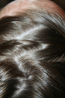 Top view of a young girl's hair being styled into “Heart Pigtail” hairstyle
