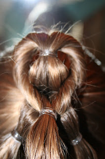 Back view of young girl's hair being styled into "Three-Leaf Clover Twists" hairstyle