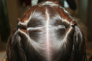 Back view of young girl's hair being styled into "Two-Leaf Clover" hairstyle