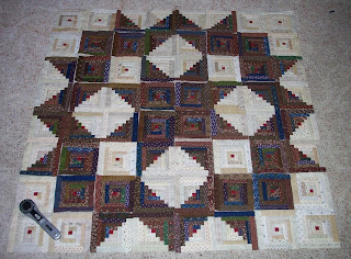 Sixty-four five inch log cabin blocks laid out to form a broken star