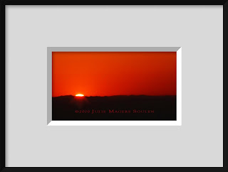 A framed photo of a brilliant red sunrise is an abstract explosion of bright red with a silhouette of the horizon.