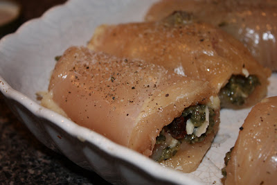 baking tin wth raw chicken roll ups seasoned with salt and pepper