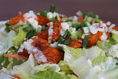 plate of lettuce and shredded carrots with buffalo chicken and blue cheese dressing