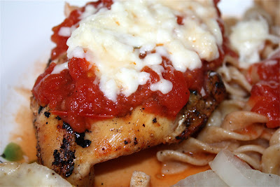 close up of piece of chicken topped with tomato sauce and cheese