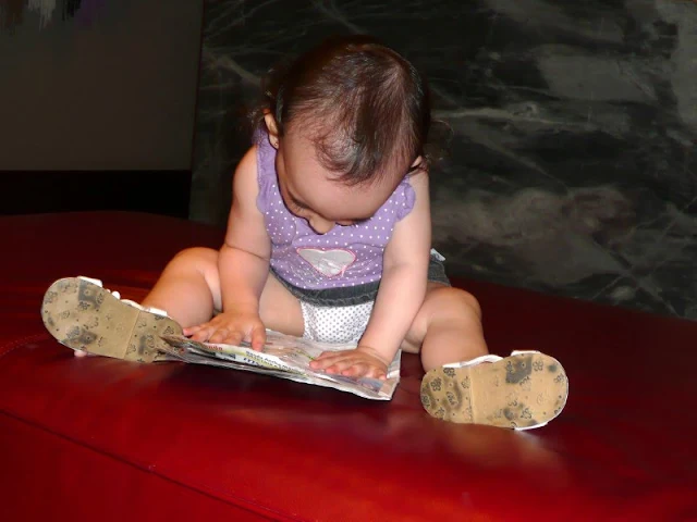 Instantáneas, nena sentada en el piso con una revista.