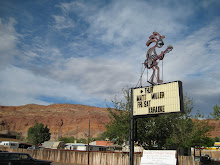 the sign in front of frankie d's, with orange cliffs of moab behind it