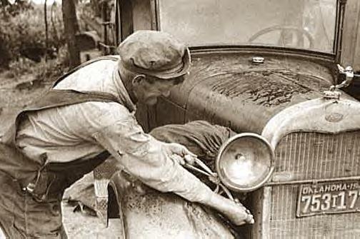 Elmer Thomas tying laundry onto car for trip to Ca., July 1939
