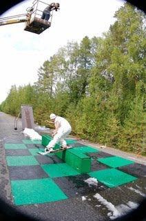 Snowboard on black and green checkered asphalt