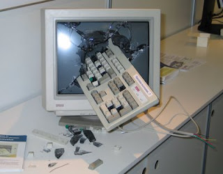 photo of a computer keyboard smashed through the monitor