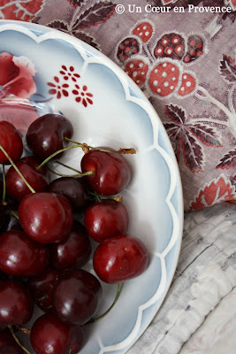 Cerises dans une assiette sarreguemine posée sur un boutis coloré de même