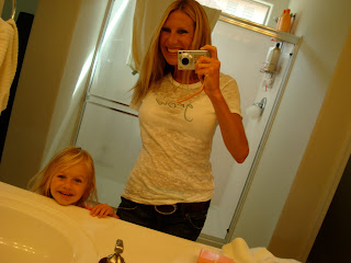 Woman and young girl smiling in bathroom mirror
