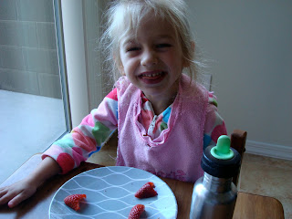 Young girl making silly face while eating strawberries