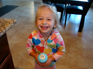 Young girl holding sippy cup smiling