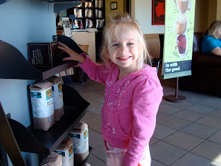 Young girl in pink standing looking at coffee products