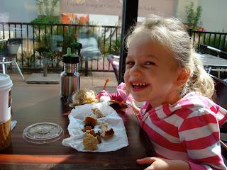 Young girl sitting at table eating snacks and smiling