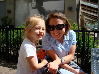 Lady in blue dress and young girl smiling outside at coffee shop