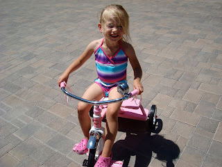 Young girl in swim suit riding tricycle