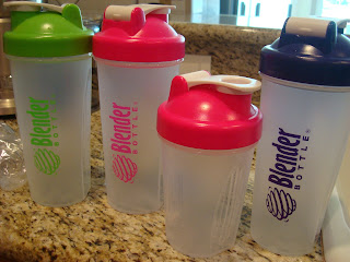 Various colors and sizes of blender bottles on countertop