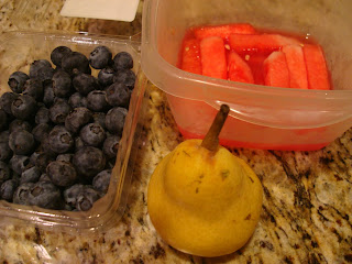 Containers of blueberries, watermelon and a pear on countertop