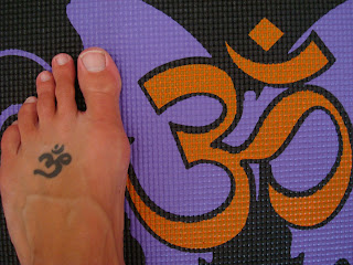 Foot with Om tattoo matching Om design on yoga mat