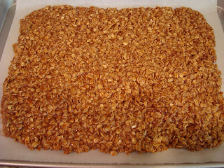 Granola spread out on parchment paper lined baking sheet