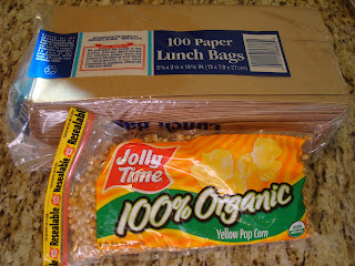 Paper lunch bags and organic yellow pop corn in packages on countertop