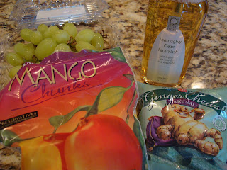 Array of frozen mango chunks, grapes, facial cleanser and ginger chews on countertop